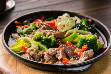 beef stew with vegetables in a frying pan over dark background