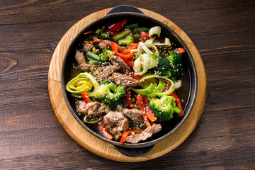 beef stew with vegetables in a frying pan over dark background