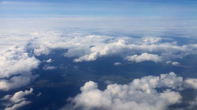 Traveling by air. View through an airplane window. Flying over the Mediterranean Sea through cirrus and cumulus clouds and little turbulence, showing Earth's atmosphere.