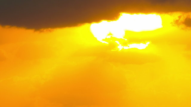 huge flaming sun rising behind a mountain disappears into clouds  telephoto