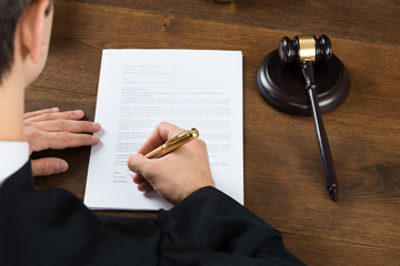 Judge Writing On Legal Documents In Courtroom