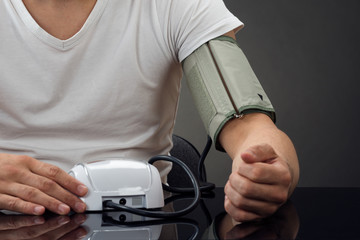 Midsection Of Man Checking Blood Pressure At Table