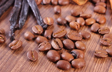 Fragrant vanilla and coffee grains on wooden surface