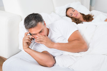 Man Busy On Phone While Woman Sleeping