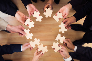 Business People Joining Puzzle Pieces In Office