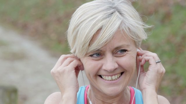 Portrait of senior woman adjusting earphones before exercising