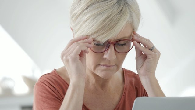 Senior Woman Having Eye Pain In Front Of Laptop