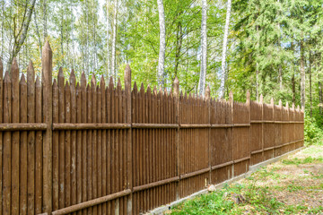 Fence made of vertical pointed logs in woodland