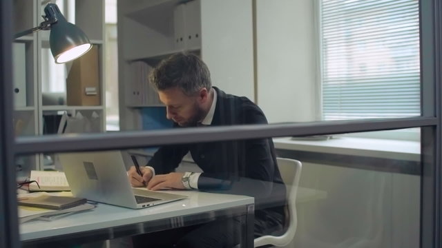 Office worker writing reminders on sticky notes and putting them on glass wall
