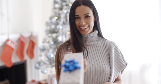 Smiling young woman holding out a Christmas gift