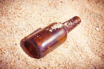 Bottle of beer glass abandoned on the beach
