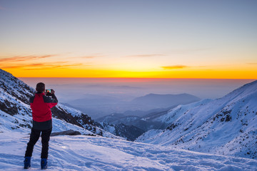 Fototapeta na wymiar Alpinist taking selfie at twilight on mountain summit