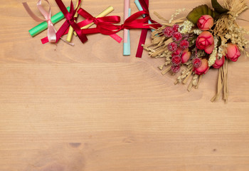 Holidays border with paper rolls and bunch of flowers on wooden
