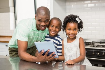 Father using tablet with his children in kitchen