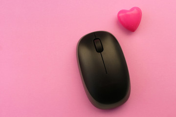 Wireless computer mouse and pink heart - love technology concept - on pink background
