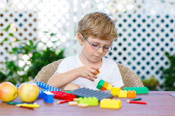 Little kid boy playing with plastic blocks