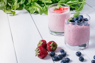 Smoothie with blueberries and strawberries on a white wooden background with a free space background