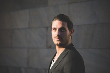 Portrait of a young handsome italian boy posing through the stre