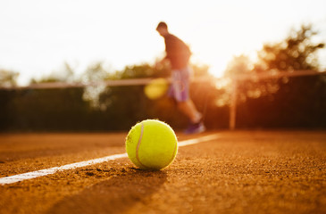 Tennis ball and silhouette of player on a clay court