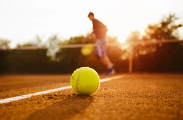Foto op Canvas Tennis ball and silhouette of player on a clay court © yossarian6