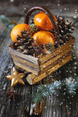 Christmas basket with tangerines, cinnamon sticks and pine cones © photosimysia
