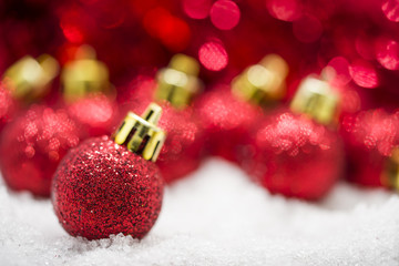 Fototapeta na wymiar Red Christmas balls on snow against red bokeh background