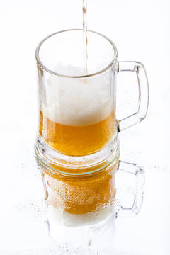 Photo of beer with reflection in glass with foam and bubbles on a white background