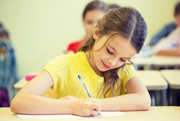 group of school kids writing test in classroom