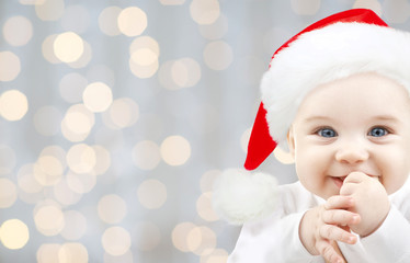 happy baby in santa hat over holidays lights