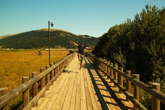 erkek manken model iskelede neşeyle zıplarken kollarını a&ccedil;ıyor