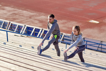 couple stretching leg on stands of stadium