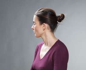 female portrait - thinking 30s woman with tied brown hair looking back for questions and nostalgia on her past,profile view,studio shot