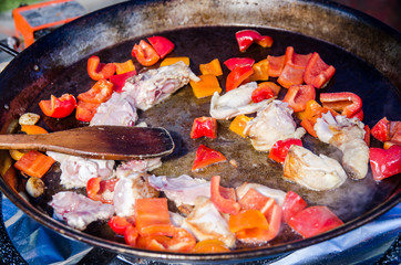 pieces meat stir fry in a frying pan  with peppers