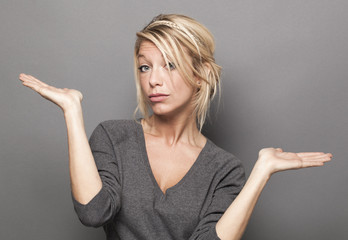 body language concept - dubious 20s blond woman weighting a product on both palms of her hands for...