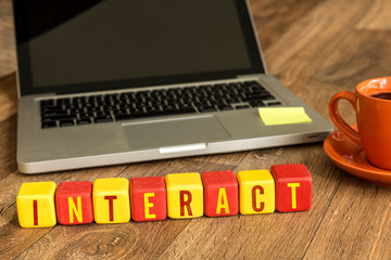 Interact written on a wooden cube in a office desk