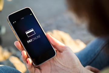 woman sitting in the street holding her smartphone with pay onli