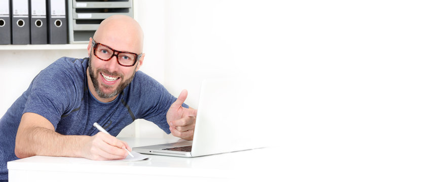 Mann notirer vor dem Computer