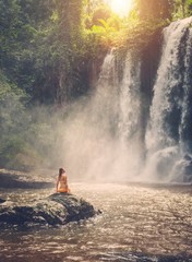 Beautiful woman sitting near waterfall enjoying the sun, Phnom Koulen at Siem Reap, Cambodia