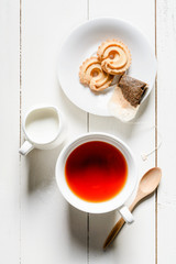 Overhead view of a cup of tea with cookies and milk