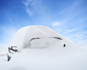 Car under snow in winter day after snowfall