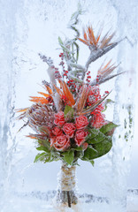 frozen bouquet of flowers with red roses in block of ice