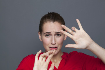 negative feelings concept - portrait of scared 20s beautiful girl defending herself behind hands...