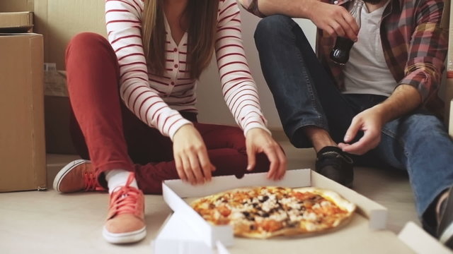 Couple are eating pizza and resting before unpacking their belongings