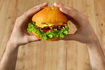 Eating Fast Food. Close Up Of Man's Hands Holding Delicious Classic American Hamburger Stacked With...