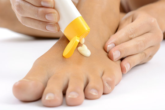 Frau massiert Fuß mit Hautcreme