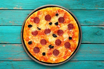 Cooked salami pizza on turquoise background