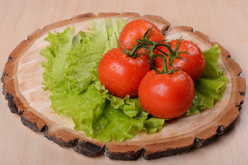 bunch of tomatoes and green sald on wooden coaster