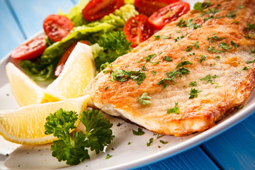 Fish dish - fried fish fillet baked potatoes and vegetables 