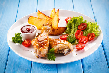 Grilled chicken legs with chips and vegetables 