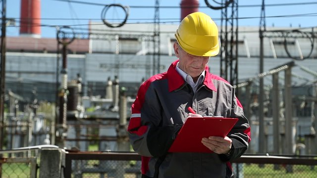 Power engineering specialist at heat station. Man writes in a worksheet. Engineering supervision at heat electric power station

